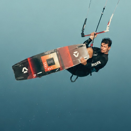 Kitesurfer holding a board underwater during a jump